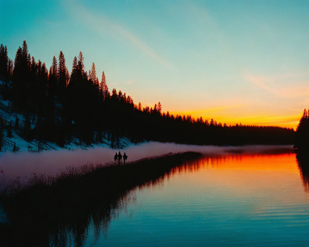 Sunset scene: Two figures walk by misty lake with orange sky and pine tree silhouettes