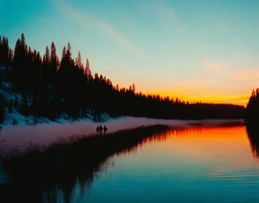 Sunset scene: Two figures walk by misty lake with orange sky and pine tree silhouettes