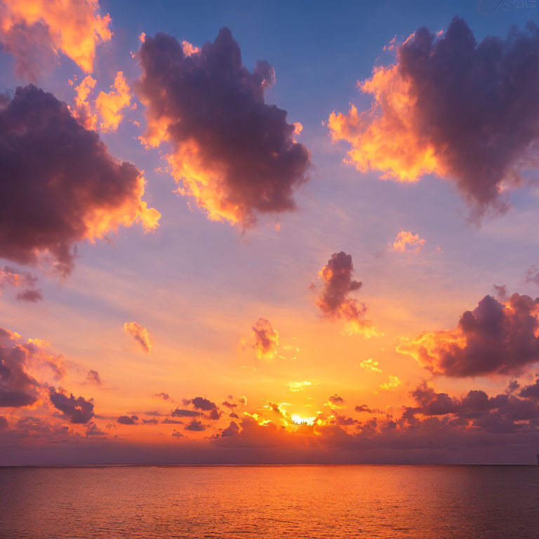 Colorful sunset over ocean with sun and clouds casting warm hues.