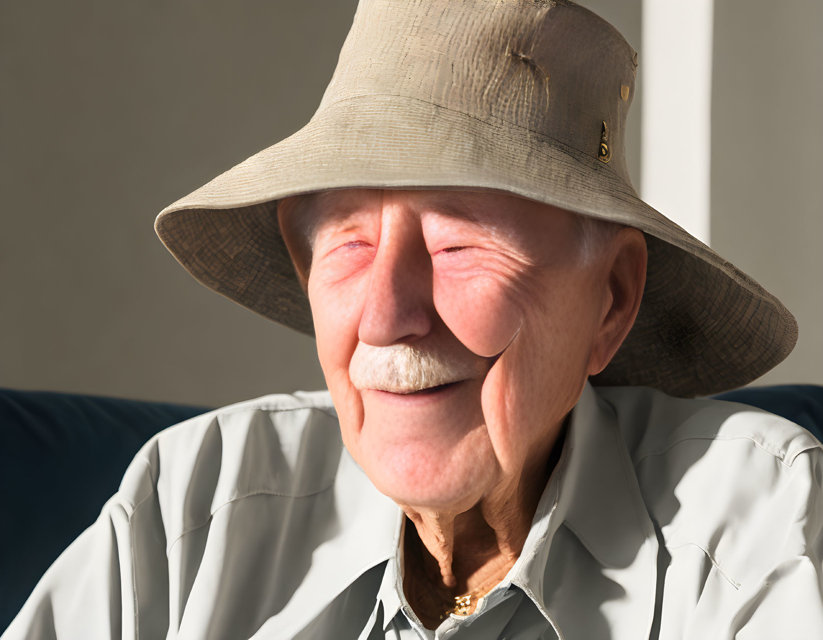 Smiling elderly man with mustache in wide-brimmed hat under sunlight