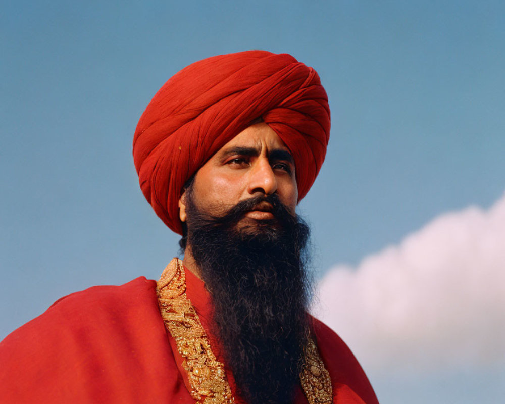 Man with Long Beard in Vibrant Red Turban and Robe under Clear Blue Sky