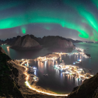 Panoramic night view of coastal town with aurora borealis