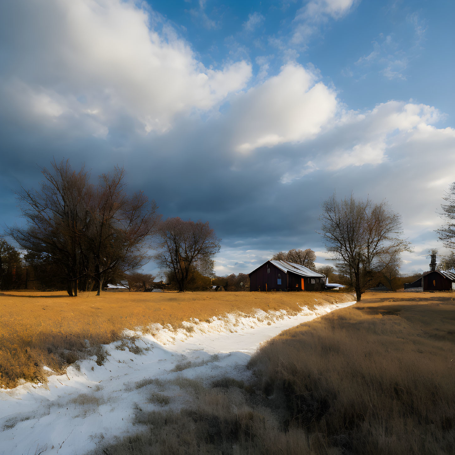 Golden field with snow patches, purple-roofed barn, leafless trees under dramatic sky