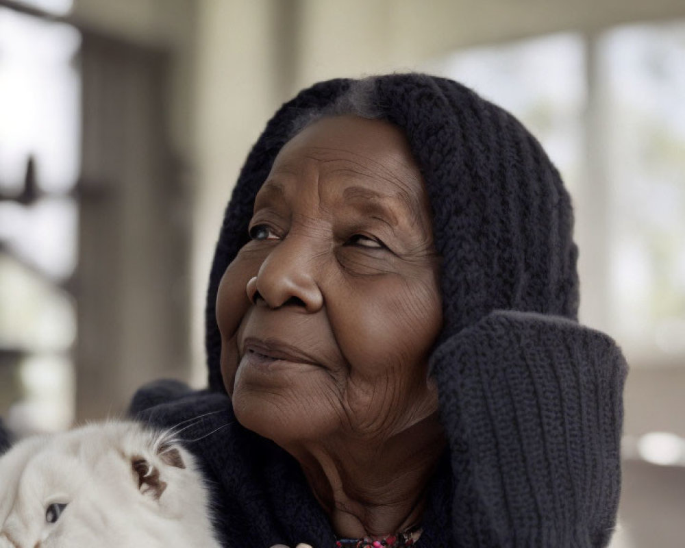 Elderly woman in knitted hat with content smile holding white cat