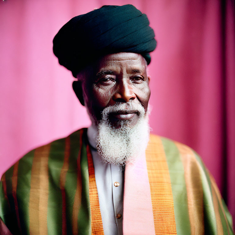 Elderly Man in Traditional Attire on Pink Background