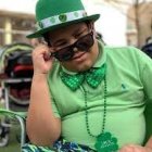 Stylized person in green outfit poses with classic car in urban setting