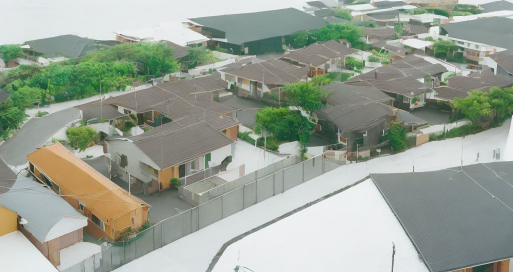 Residential area with gray-roofed houses, trees, and winding road