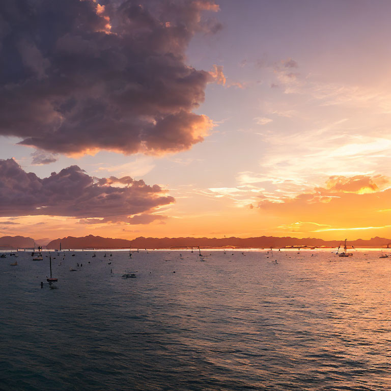 Tranquil sunset scene with boats, mountains, and orange sky