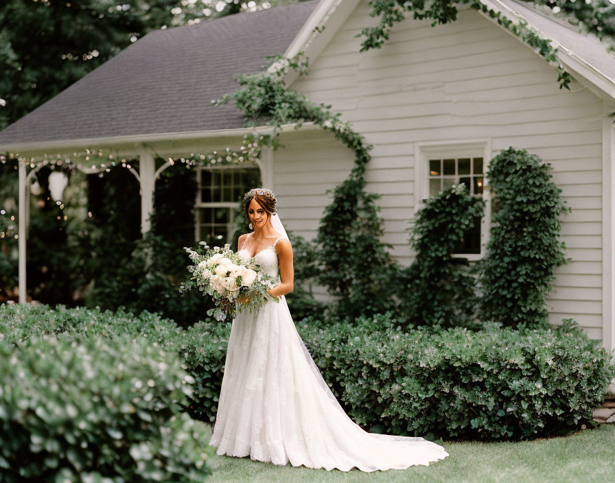 Bride in white gown with bouquet at elegant white house venue