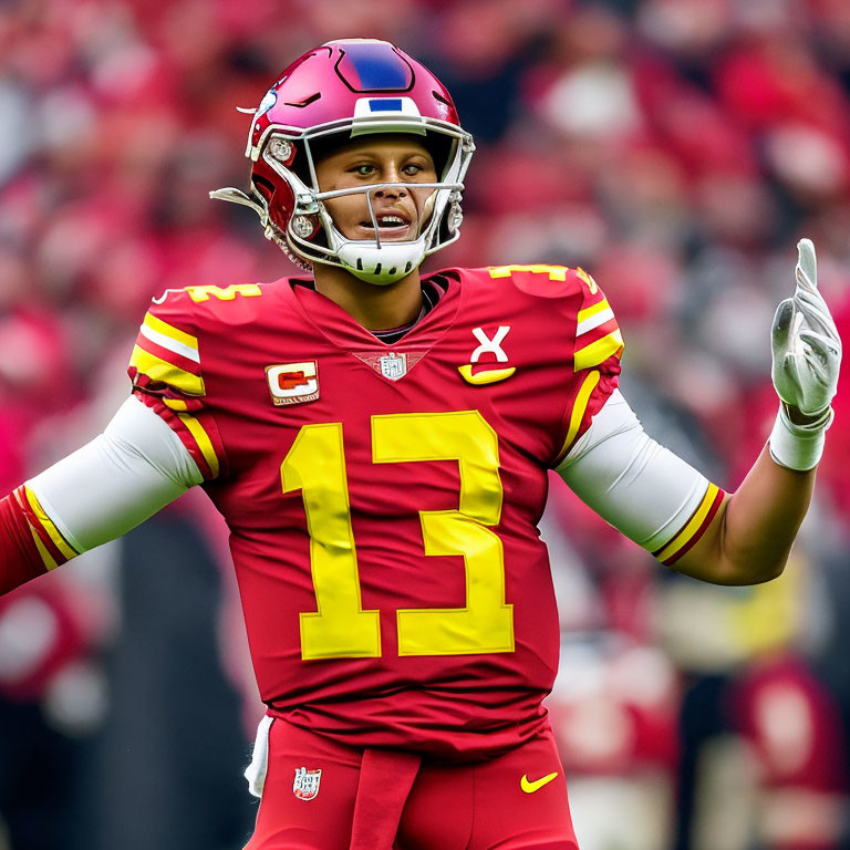 Football player in red and yellow uniform with helmet and number 13 gesturing on field