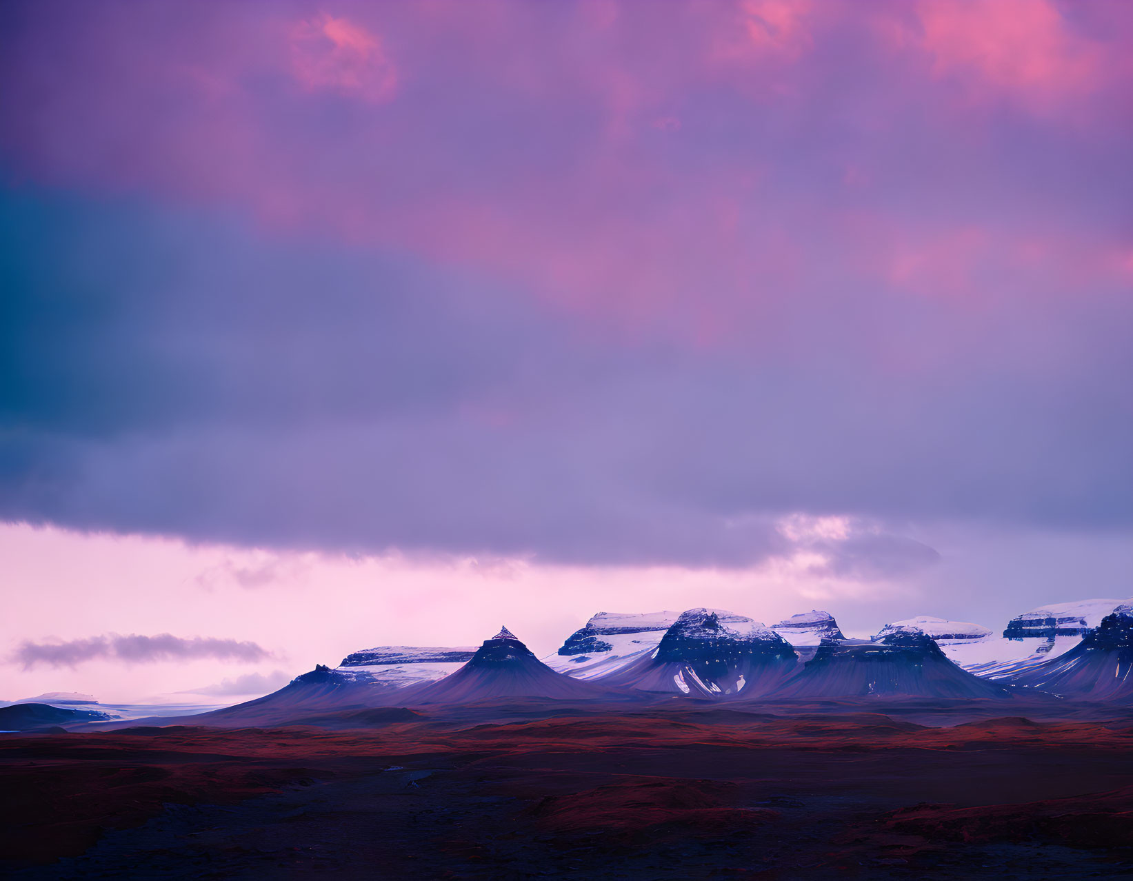 Vibrant sunset over dark mountains and red plains