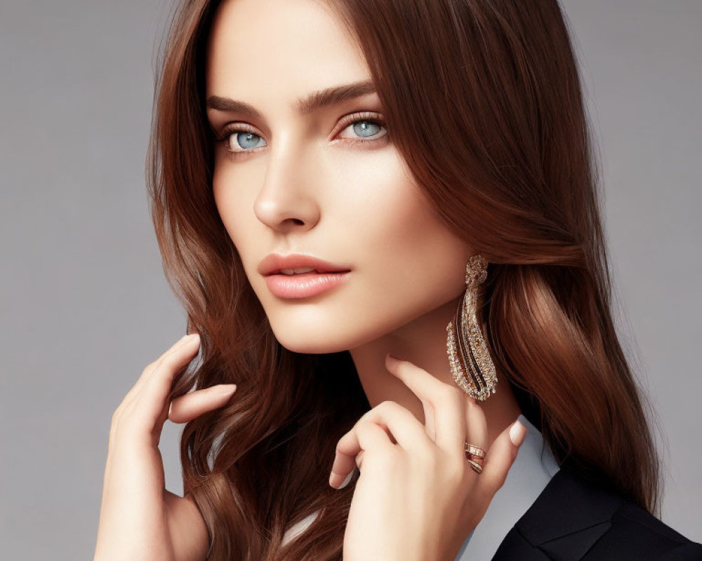 Portrait of a woman with long brown hair and blue eyes on gray background