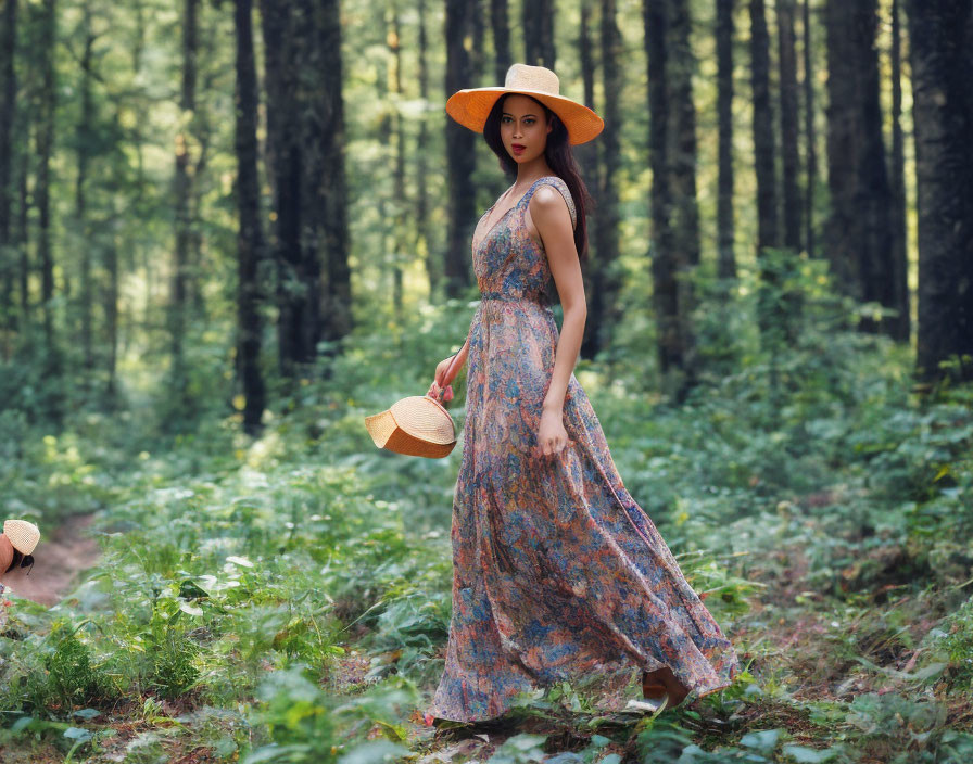 Woman in floral dress and hat standing in forest among tall trees