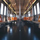 Clean Subway Train Interior with Orange Seats and Glossy Metal Poles