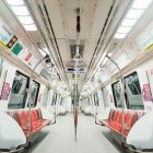 Empty modern subway car with white interiors, red seats, and bright lighting