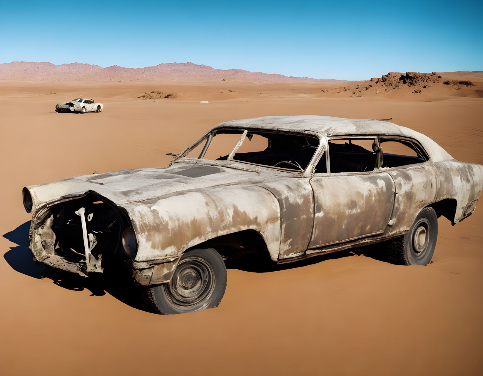 Abandoned car in vast desert under clear blue sky