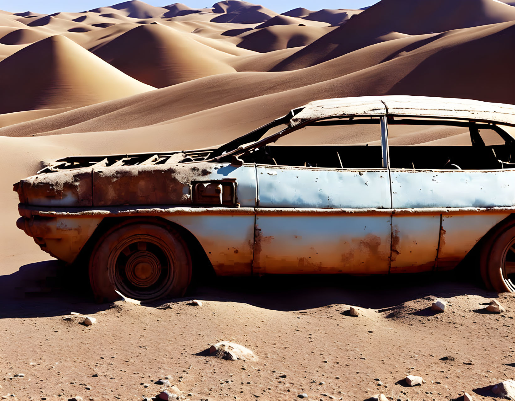 Abandoned rusty car in desert with sand dunes and clear sky