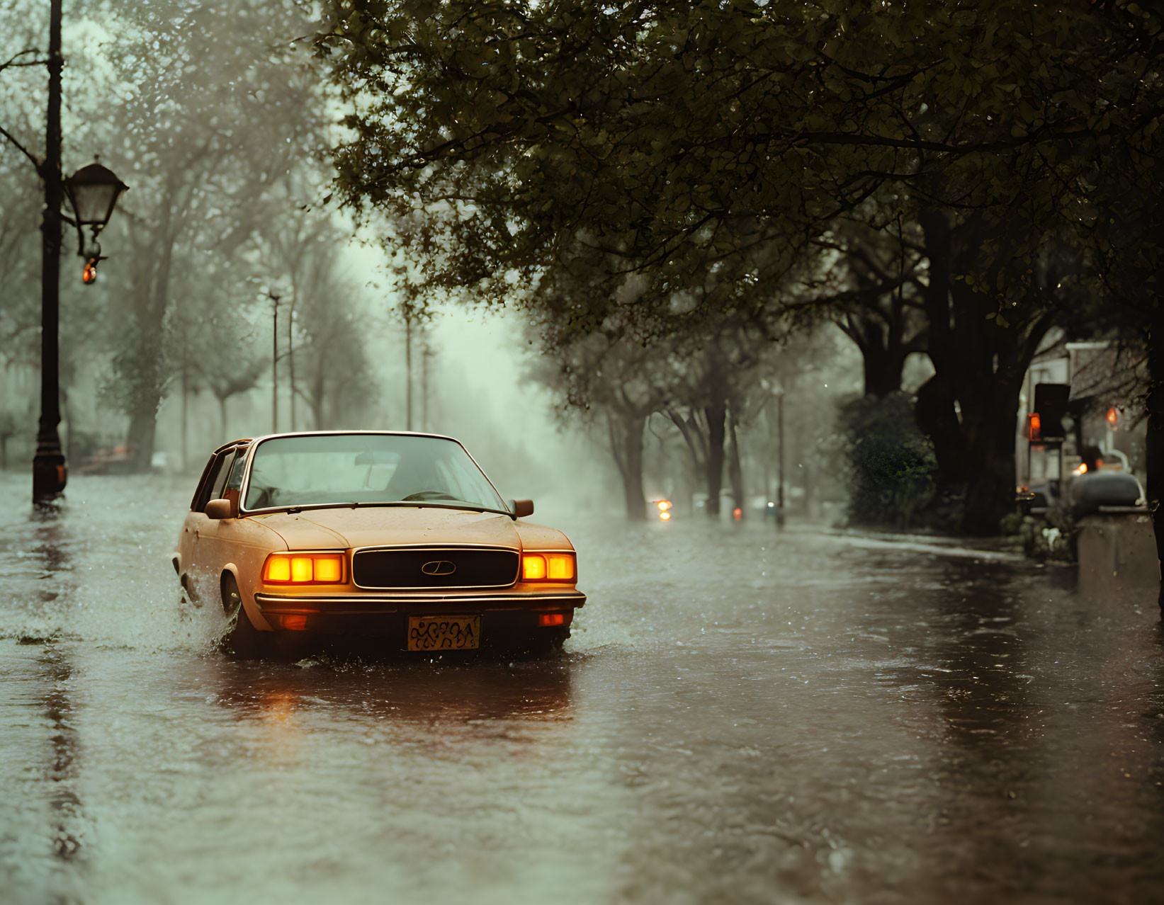 Vintage car drives through flooded street with mist and streetlights.