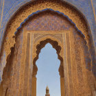 Intricate Islamic patterns frame a minaret and dome in arched doorway view