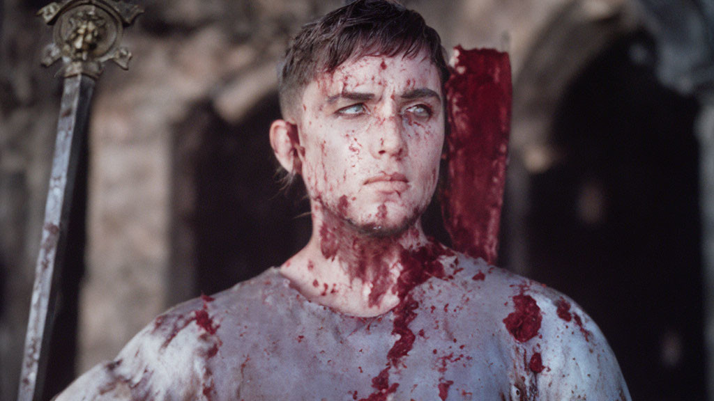 Man with blood-splattered sword in somber expression