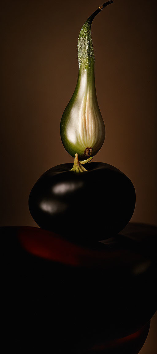 Green pear on black stones with soft lighting and shadows