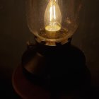 Oversized illuminated light bulb on reflective surface against starry backdrop