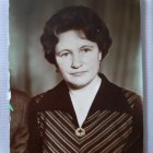 Vintage makeup portrait of a woman with black wavy hair and green eyes in a brown suit.