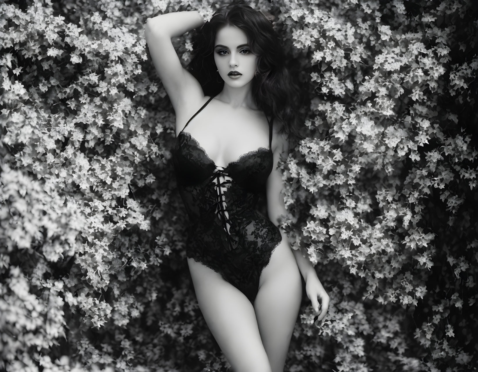 Monochrome portrait of confident woman in lingerie among flowers