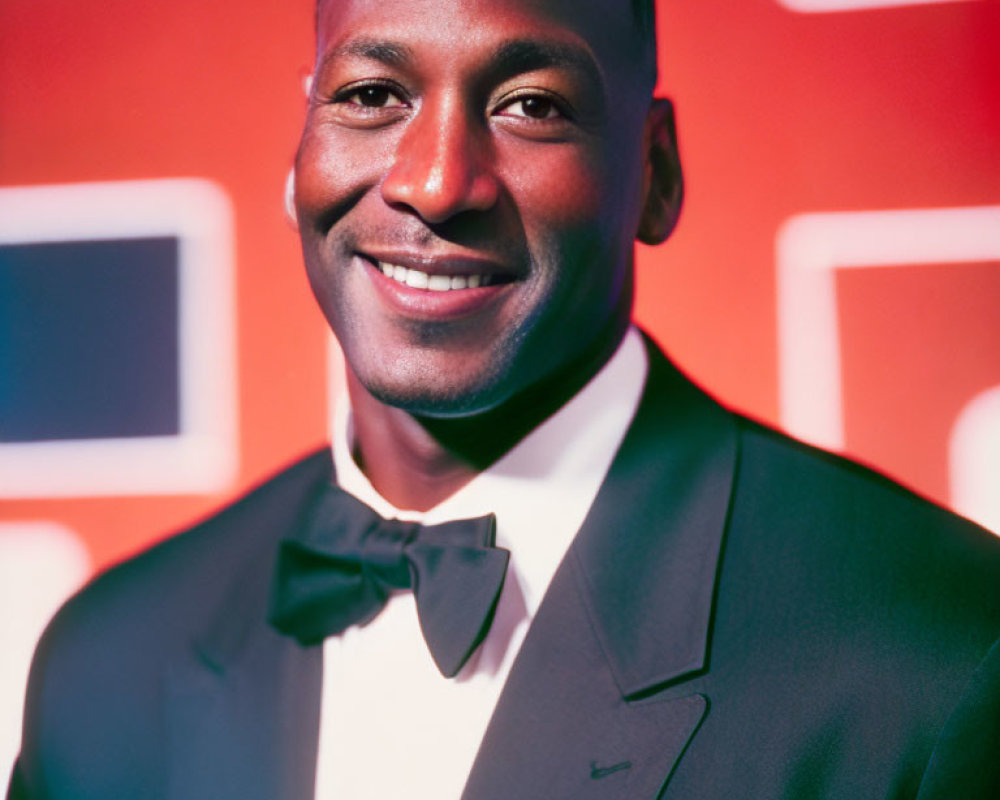 Smiling man in black tuxedo with colorful geometric backdrop