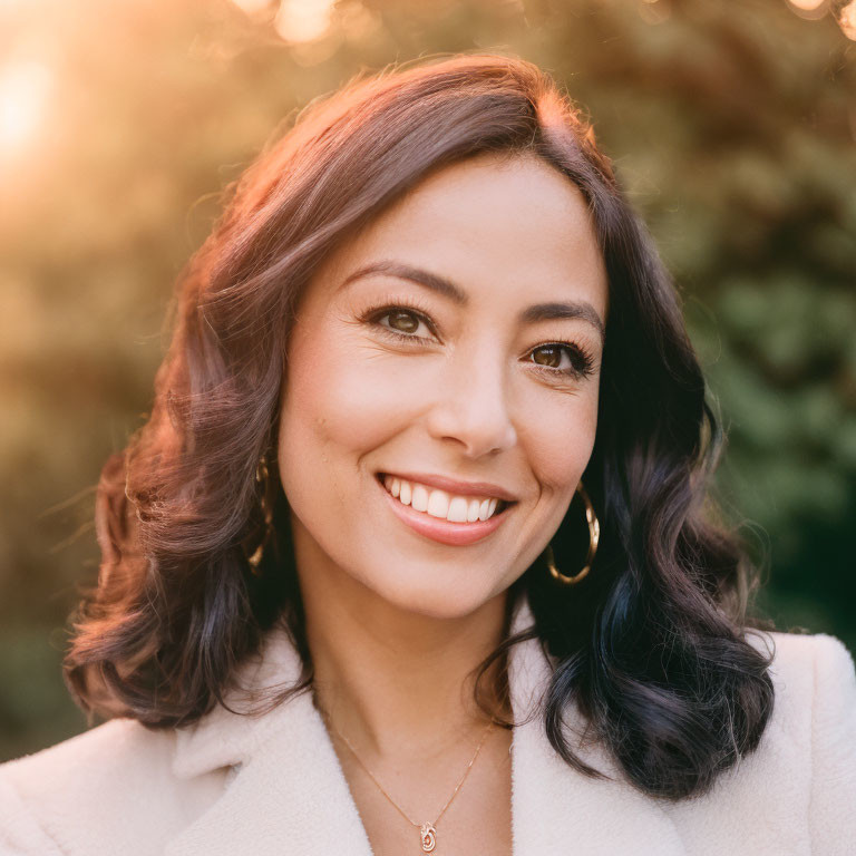 Smiling woman with wavy hair in white coat and jewelry