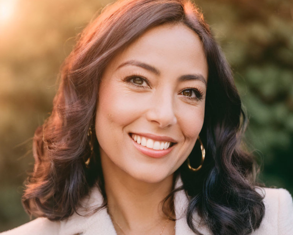 Smiling woman with wavy hair in white coat and jewelry