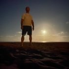 Astronaut in spacesuit on rocky terrain under twilight sky with sun and moon.