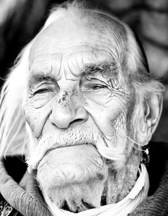 Elderly person with deep wrinkles and white hair gazes thoughtfully.