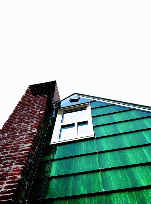 Modern building with brick wall and green glass facade against white sky