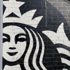 Stylized Starbucks logo mural with monochrome siren figure on exterior wall