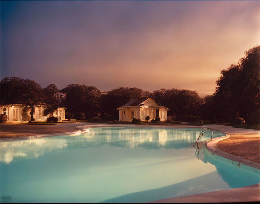 Tranquil pool reflecting pastel sky with white buildings and lush trees