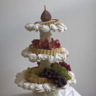 Three-tiered castle cake with fruit, butterflies, and birds on neutral background