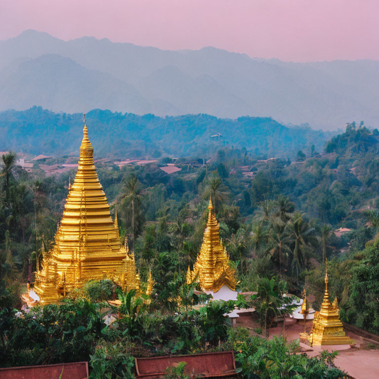 Golden Pagodas Surrounded by Greenery and Mountains at Twilight