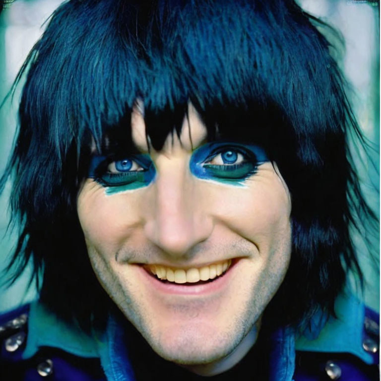 Portrait of a person with blue eye makeup and black hair in a blue outfit