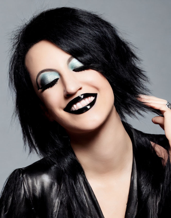 Woman with Black Lipstick and Turquoise Eyeshadow Smiling in Black Outfit