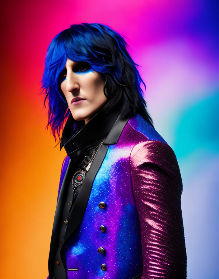 Blue-haired person in glittery blue-purple jacket on colorful backdrop