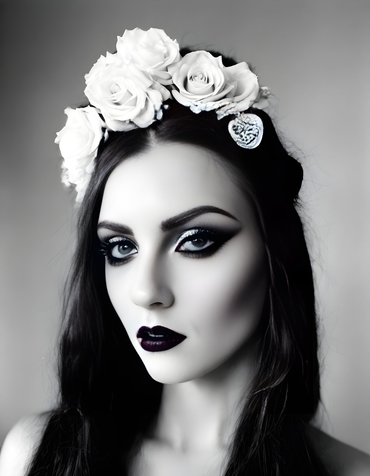 Monochromatic portrait of woman with dark makeup and white roses.