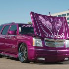 Custom purple lowrider car with ornate engine in city setting.