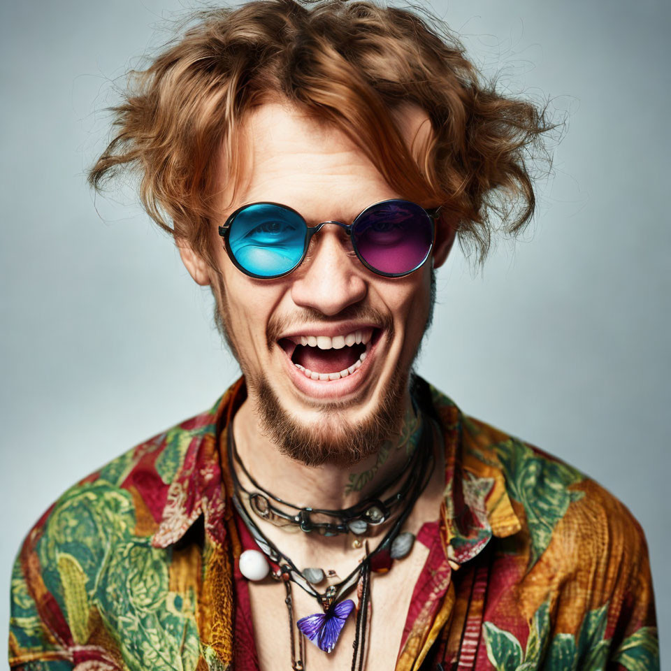 Colorful Young Man in Round Sunglasses Laughing on Blue Background