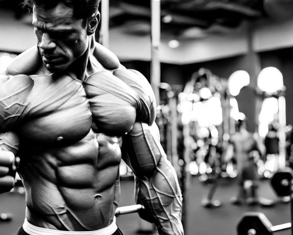 Muscular person flexing biceps in gym setting with workout equipment, black and white photo showcasing muscle