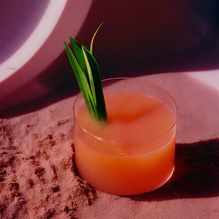 Tropical cocktail with green garnish on sand under palm leaf shadow