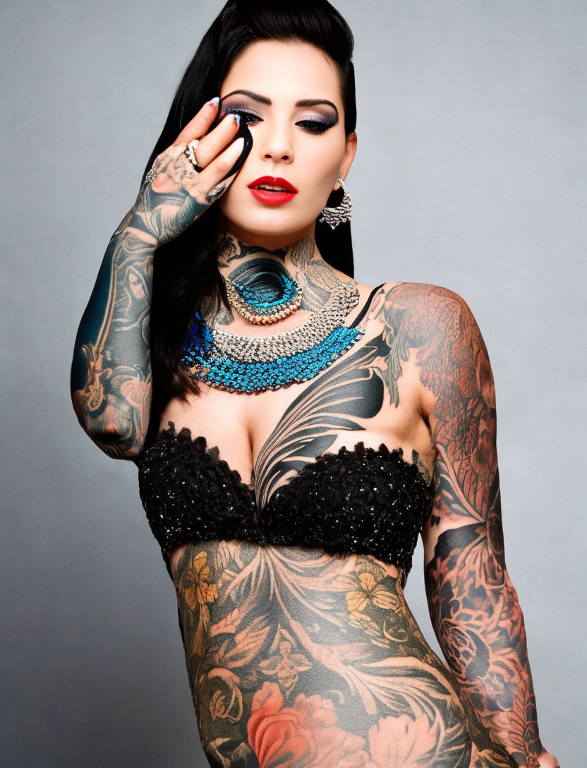 Woman with bold makeup and tattoos posing in strapless top and beaded necklace