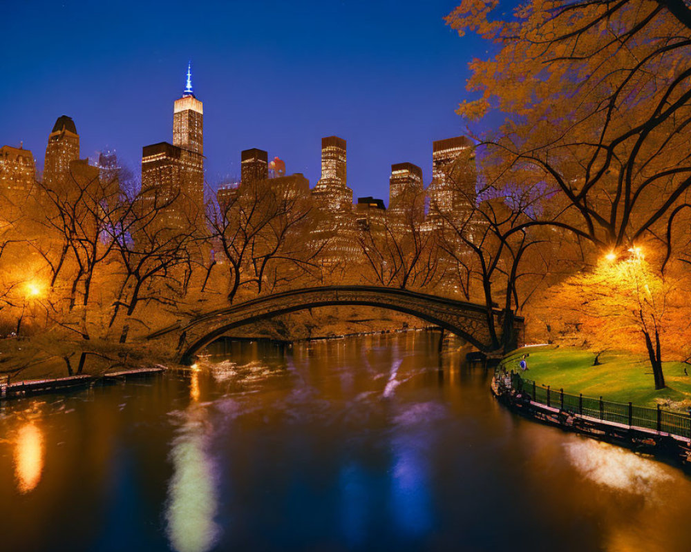 Tranquil night scene of reflective river and stone bridge in Central Park