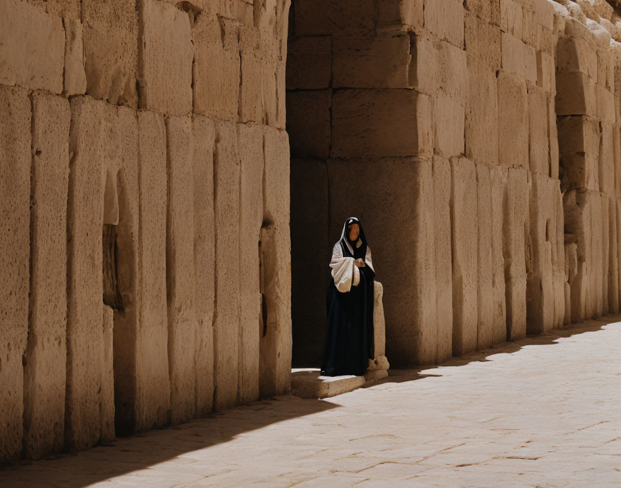 Traditional Attire Figure by Ancient Stone Walls in Bright Sunlight