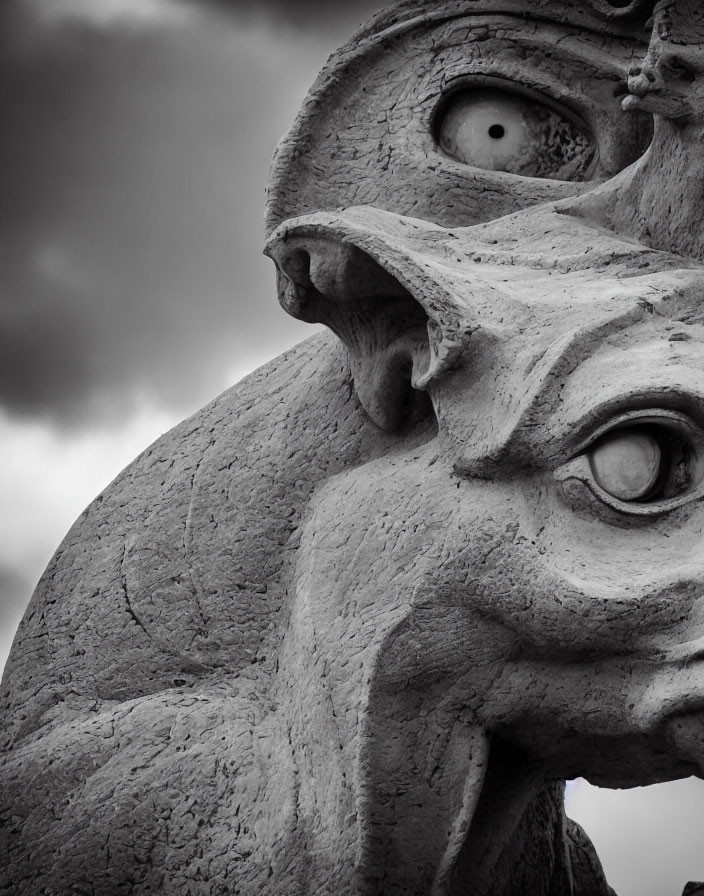 Stone sculpture with dramatic curves and intense gaze under cloudy sky